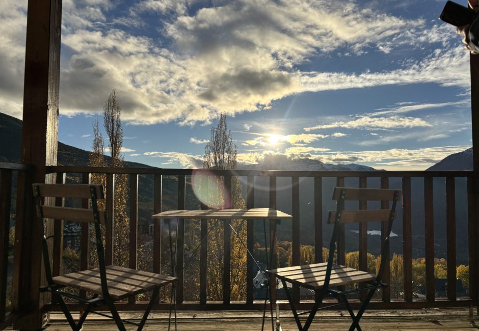 balcón de apartamento vacacional en el valle de benasque con mesa y sillas para disfrutar de las vistas a la montaña